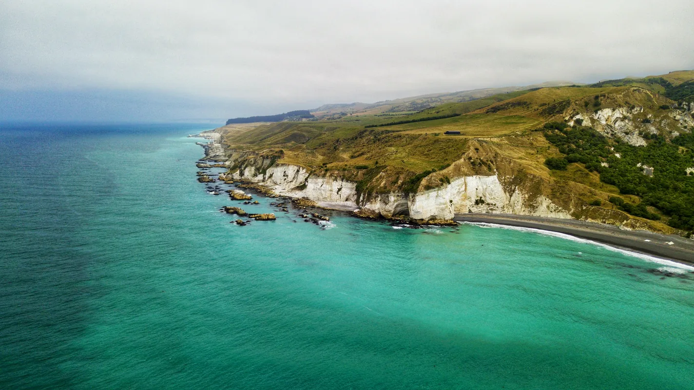 Aerial view of turquoise water breaking against white coastal cliffs